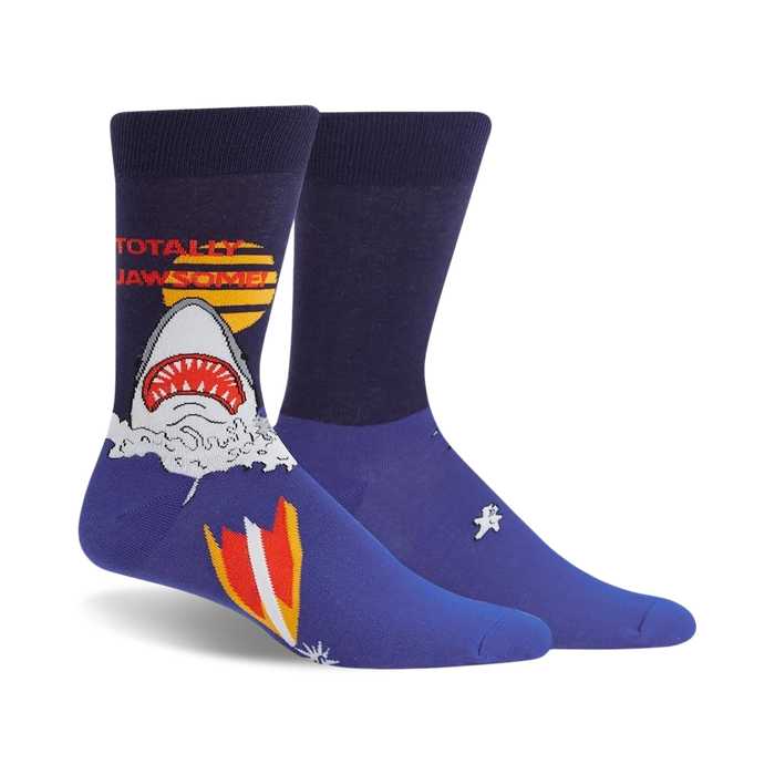 Pair of navy blue crew socks featuring a graphic of a shark emerging from water with a retro surfboard design and 'Totally Jawsome!' text.