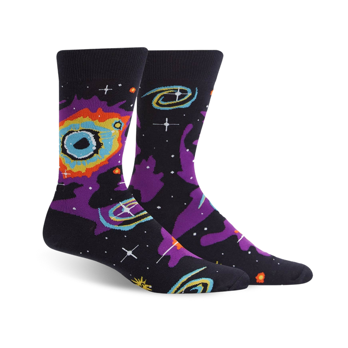 A pair of crew socks with a space-themed design.  The dark background features swirling nebulas in purple, orange, and teal, along with yellow stars. }}