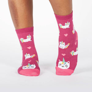 A pair of pink socks with a pattern of cartoon cats with unicorn horns and tails.