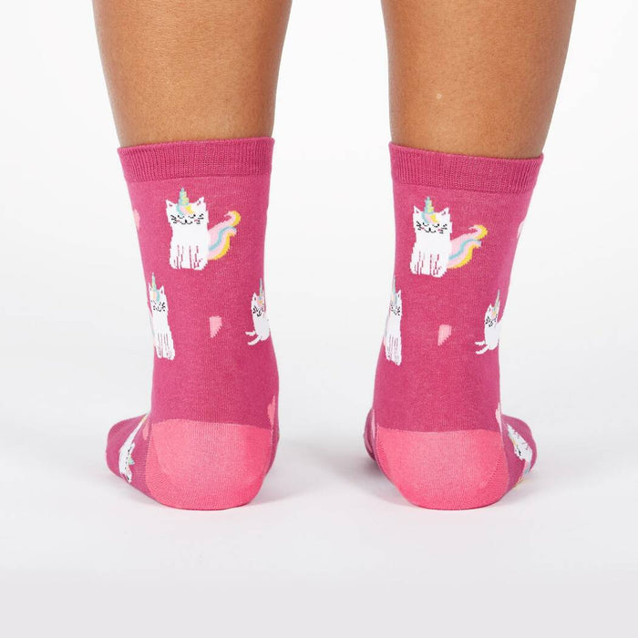 A pair of pink socks with a pattern of cartoon cats with unicorn horns and tails.