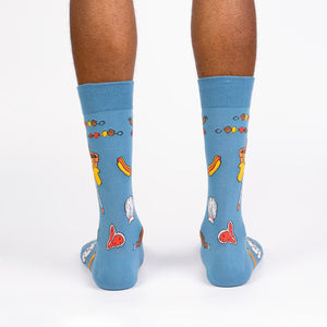 A pair of blue socks with a pattern of cartoon hot dogs, steaks, and grilling accessories.