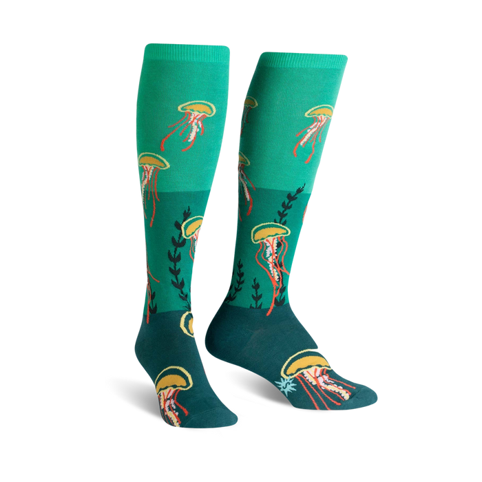 A pair of teal knee-high socks adorned with whimsical jellyfish and seaweed designs. Perfect for adding a touch of ocean magic to your outfit! }}
