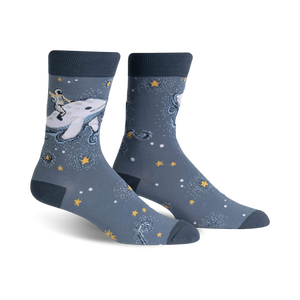 Pair of crew socks in blue and white. Design features an astronaut riding a whale amidst stars and sparkles.