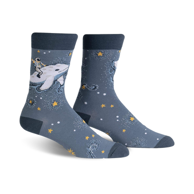 Pair of crew socks in blue and white. Design features an astronaut riding a whale amidst stars and sparkles.