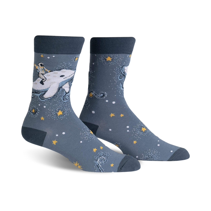 Pair of crew socks in blue and white. Design features an astronaut riding a whale amidst stars and sparkles.