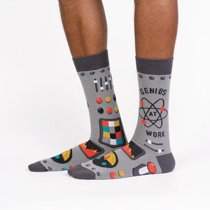Lifestyle shot of a person wearing a pair of gray 'Genius at Work' socks, showcasing how they look on the feet.