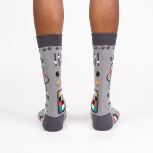 Rear view of a pair of gray 'Genius at Work' socks, showing the full design on the back of each sock.