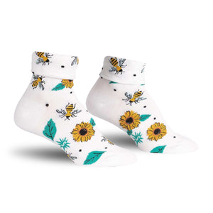 A pair of white socks with a pattern of sunflowers, bees, and leaves in green, yellow, and brown.