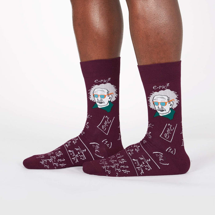 A pair of maroon crew socks with a pattern of Albert Einstein's face and equations written in white and green.