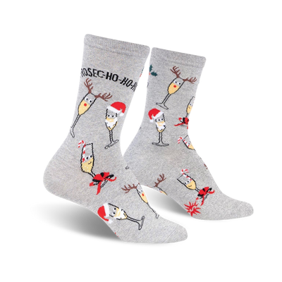 Pair of grey crew socks with a festive design. Features champagne glasses wearing Santa hats and reindeer antlers, along with candy canes and holly.