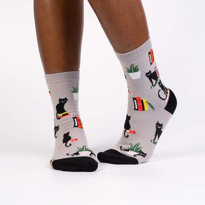 Lifestyle shot of model wearing 'Booked For Meow' socks, showcasing how they look on feet.
