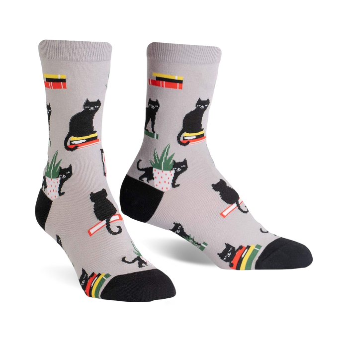 gray crew length women's socks with black cats sitting on books and potted plants  
