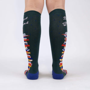 Rear view of the socks showing the design on the back of the legs.  These are dark green knee-high socks with a book stack design.