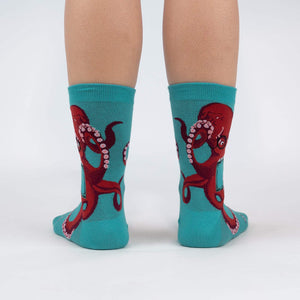 A pair of teal socks with a red octopus wearing glasses on each sock.