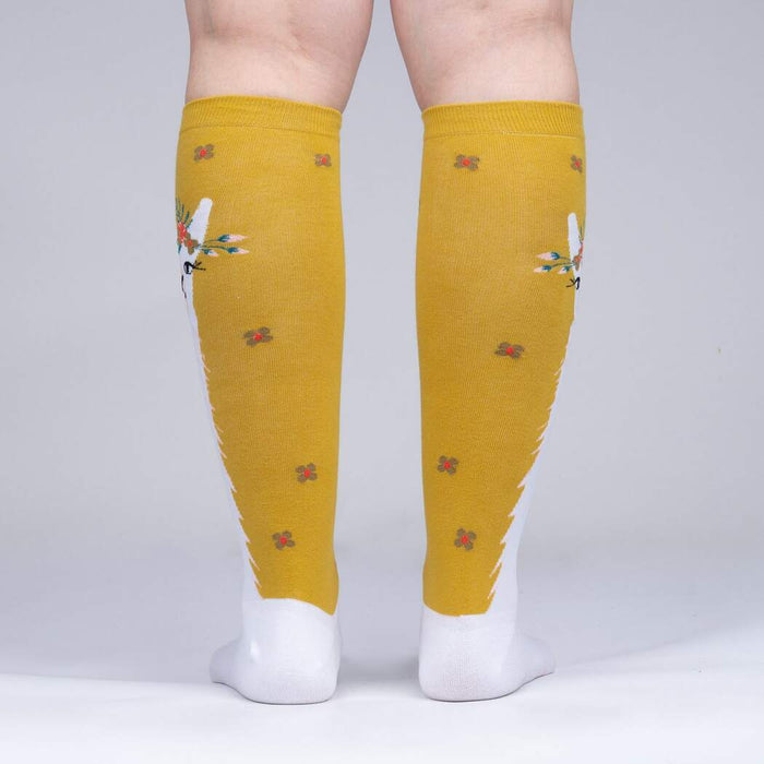 A pair of yellow and white knee-high socks with a llama face on the back of each sock.