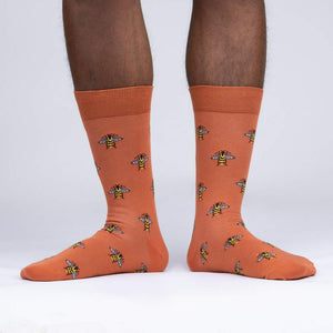 A pair of orange socks with a pattern of cartoon bees.