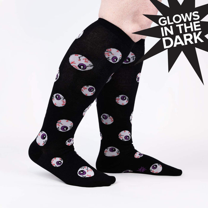 Lifestyle shot showing the All Eyes On Me Glow socks on a person's legs, highlighting their glow-in-the-dark feature.
