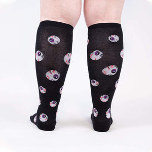 Rear view of a person wearing the All Eyes On Me Glow knee-high socks, showcasing the eyeball pattern on the back of the socks.
