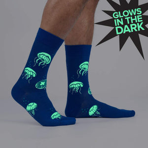 Close up shot of the 'Nice to Sea You' glow-in-the-dark jellyfish socks in the dark, highlighting the glow effect.