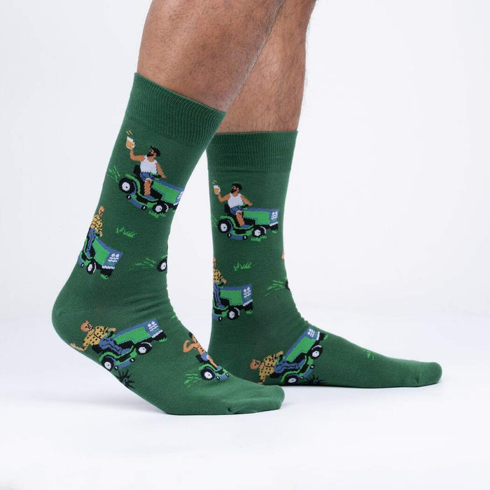A pair of green socks with a pattern of cartoon men mowing lawns while drinking beer.
