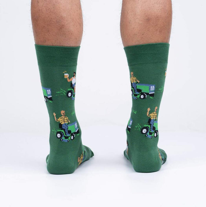 A pair of green socks with a pattern of cartoon men mowing lawns while drinking beer.