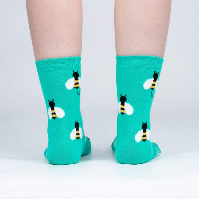 A pair of teal socks with a pattern of cartoon bees.