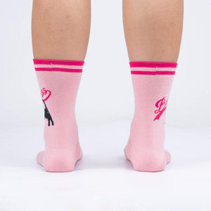 Rear view of a person's legs wearing pink 'Bad Ass Cat' socks, showing the full design on the back of the socks.