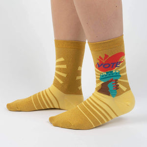 A pair of yellow socks with a colorful pattern of suns and birds on the back.