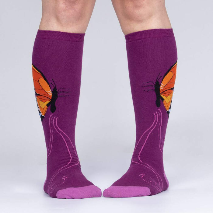 A pair of purple knee-high socks with a butterfly pattern.