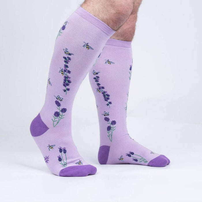 A pair of purple knee-high socks with a lavender flower and bee pattern.
