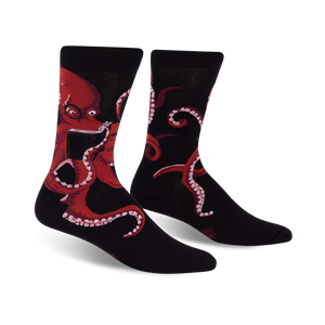 Pair of black crew socks with a red octopus reading a book; shown from the front.