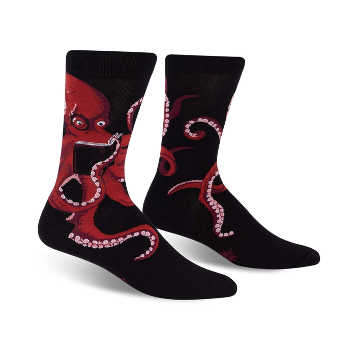 Pair of black crew socks with a red octopus reading a book; shown from the front.