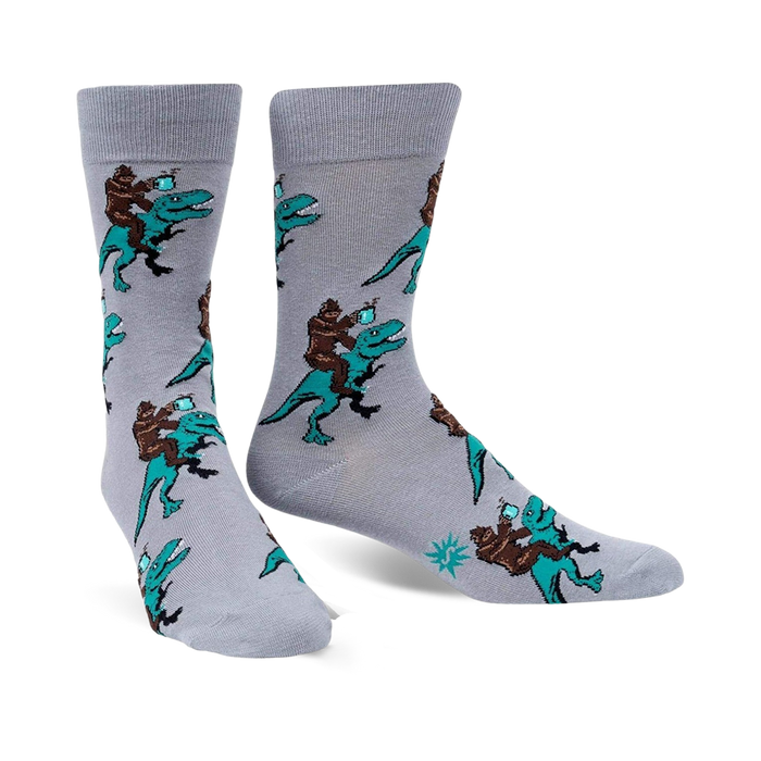 men's gray crew socks featuring bigfoot riding dinosaurs in black, brown, and teal.   }}