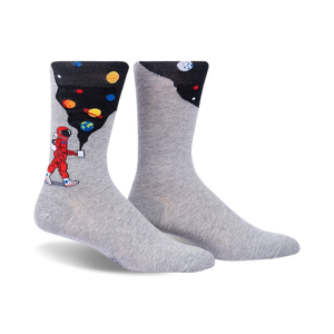 Pair of grey crew socks with a design featuring an astronaut painting planets onto a dark background.