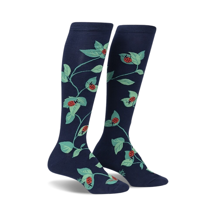 Pair of navy blue knee-high socks with a repeating pattern of ladybugs and green leaves.