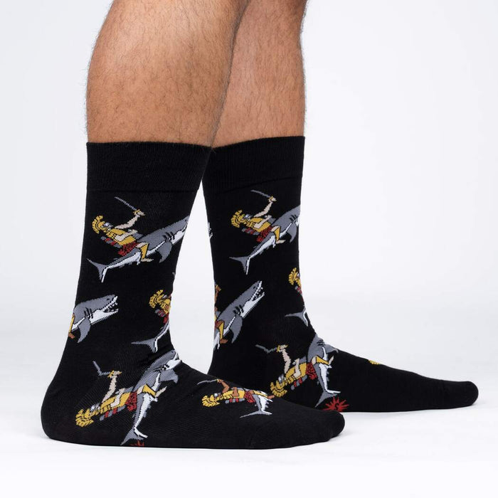 A pair of black socks with a pattern of cartoon Vikings battling sharks.