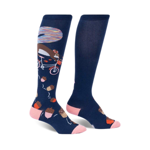 Pair of navy blue knee-high socks with a whimsical design: a squirrel riding a bicycle amidst acorns and a colorful background detail.