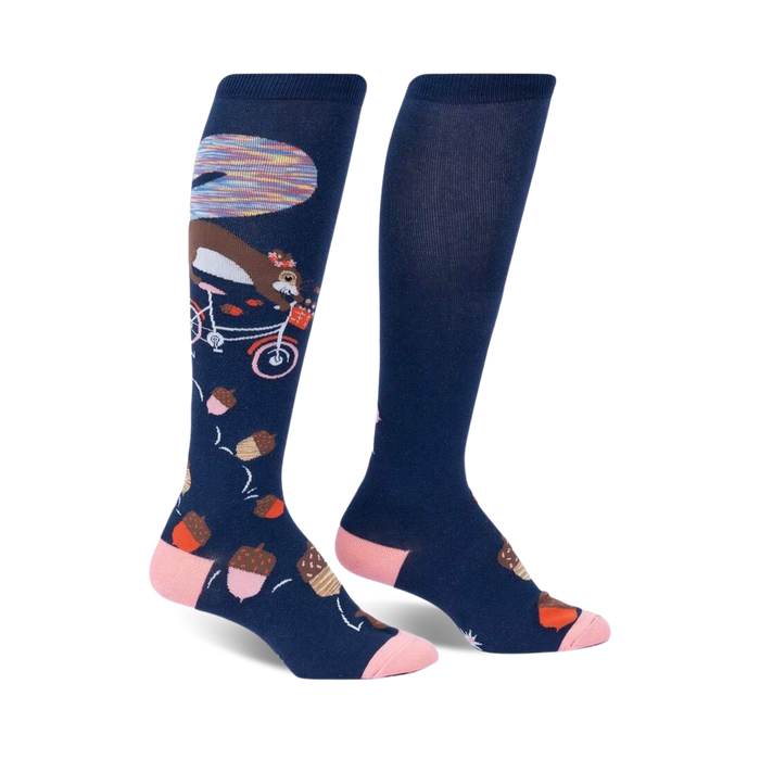blue knee-high socks featuring a pattern of brown squirrels riding pink bicycles, and brown acorns with pink tops. fall-themed design.  