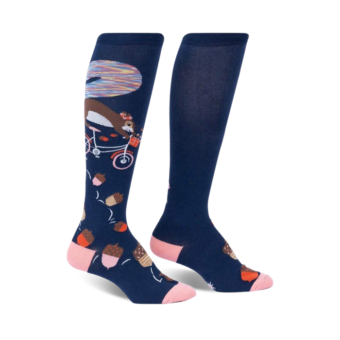 Pair of navy blue knee-high socks with a whimsical design: a squirrel riding a bicycle amidst acorns and a colorful background detail.