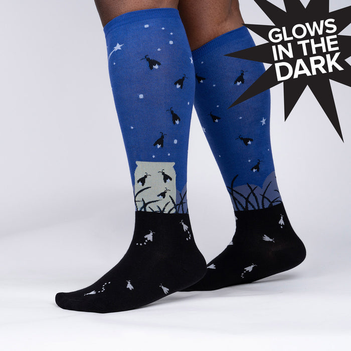 A pair of black and blue socks with a pattern of fireflies and a mason jar. The socks are described as glowing in the dark.