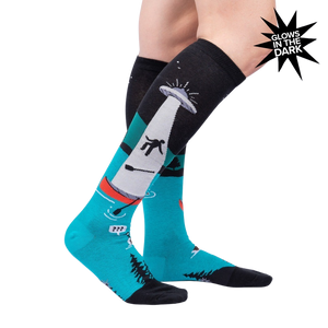 Lifestyle photo showcasing the 'Out of Boaty Experience' glow-in-the-dark socks on a model's legs.