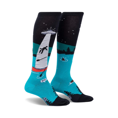 Pair of teal and black knee-high socks depicting a humorous alien abduction scene on a lake at night. The socks glow in the dark.
