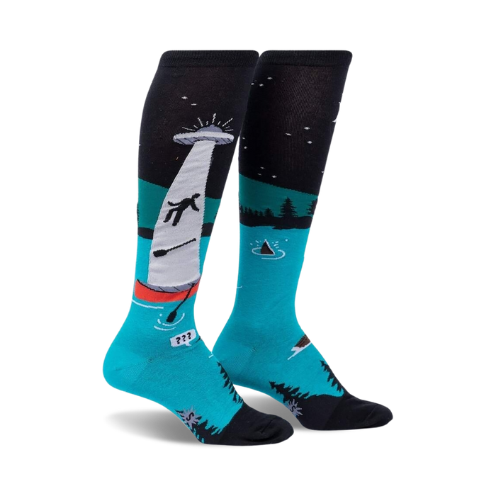 Pair of teal and black knee-high socks depicting a humorous alien abduction scene on a lake at night.  The socks glow in the dark.