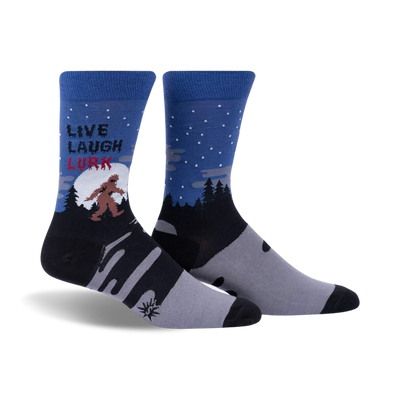 Pair of crew socks in blue, gray, and black, showing a Bigfoot design in a snowy forest scene with the text 'Live, Laugh, Lurk'.