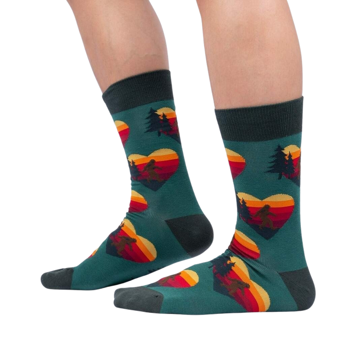 Lifestyle shot showing the socks on a person's legs; teal socks with Sasquatch and sunset heart design.