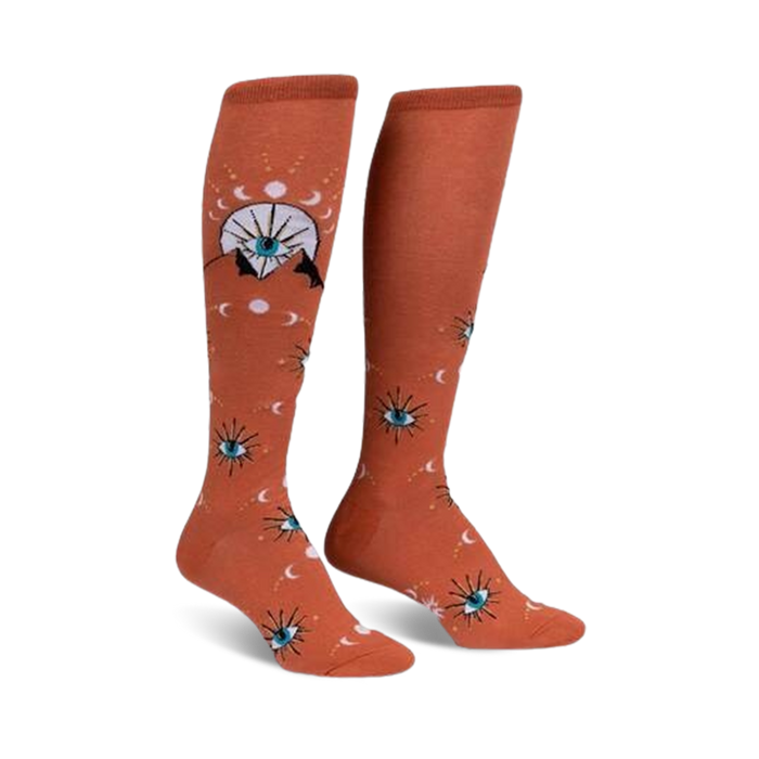 Pair of burnt orange knee-high socks with a repeating pattern of stylized eyes, moons, and celestial symbols. }}