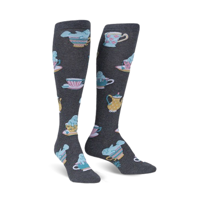 Pair of knee-high socks in dark gray featuring a pattern of manatees relaxing in pastel teacups and teapots. }}