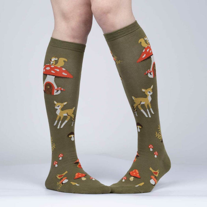 A pair of green knee-high socks with a pattern of mushrooms, leaves, and woodland creatures.