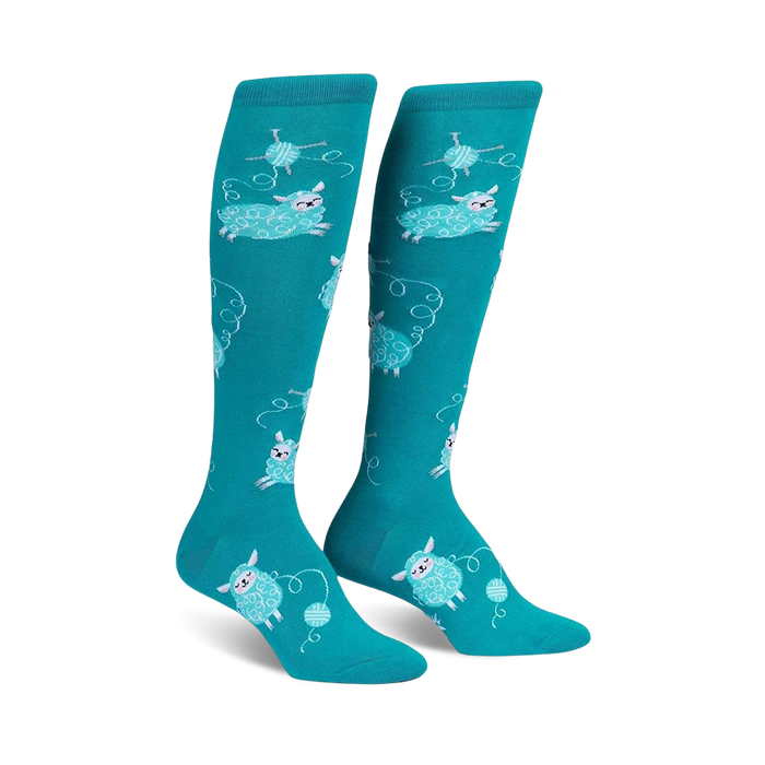 Pair of teal knee-high socks with a repeating pattern of light blue sheep playfully interacting with balls of yarn. }}
