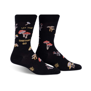 Pair of black crew socks featuring a whimsical mushroom design and the phrase 'Let That Shiitake Go'.  Red and gold mushroom illustrations scattered across the socks.